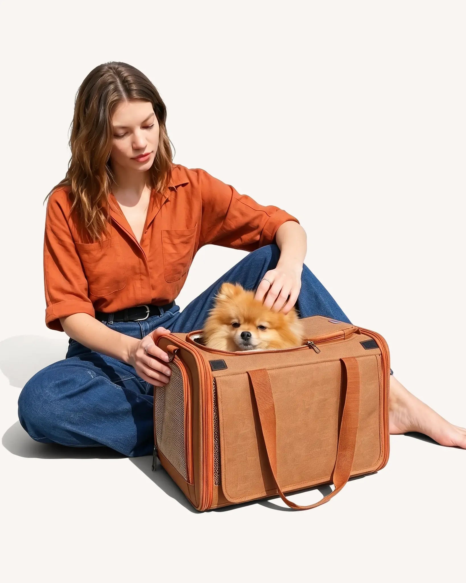The model sat on the floor, stroking the puppy that was placed in the soft-side carrier