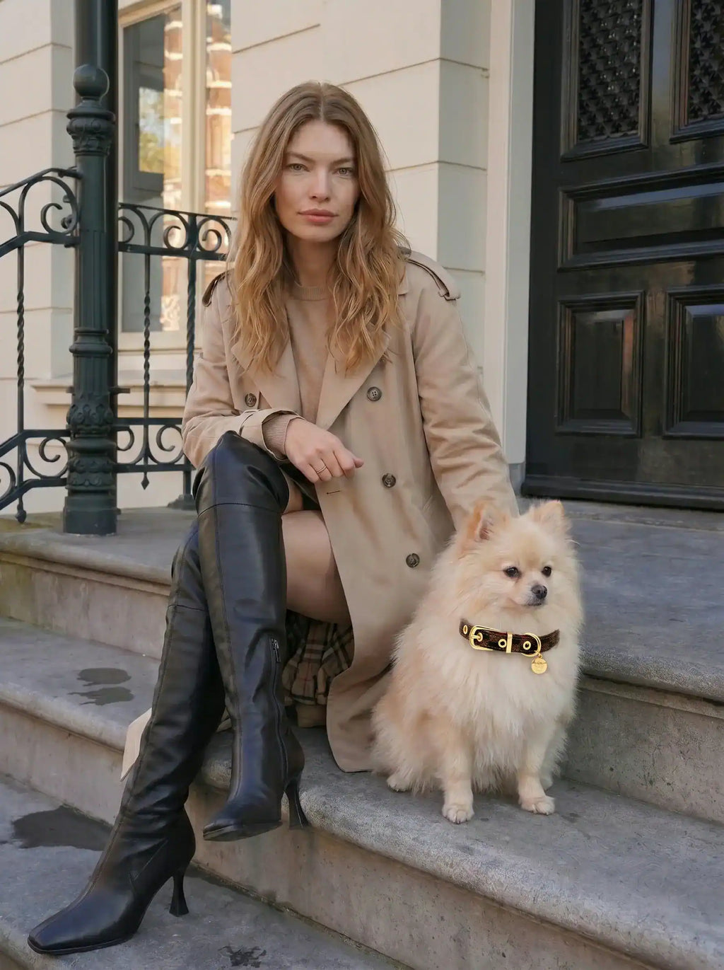 Model is sitting on the steps, with a Pomeranian wearing a collar sitting beside.
