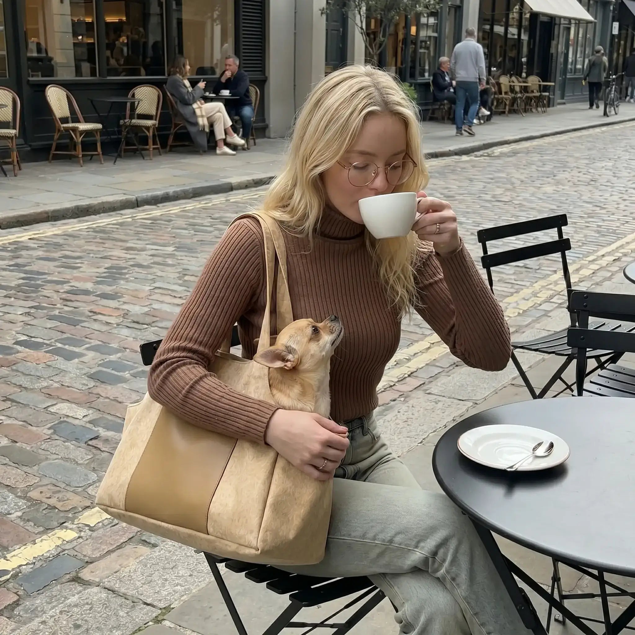 woman drinking coffee while carrying a Chihuahua by carrier bag