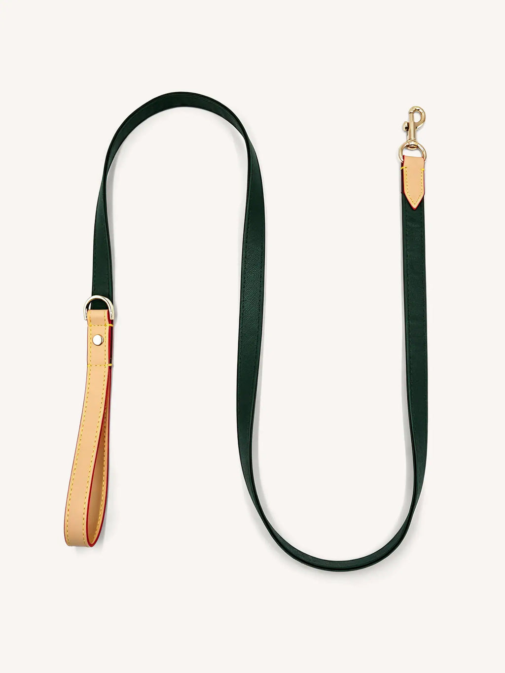 A dark green leather leash with gold hardware is lying flat on the ground