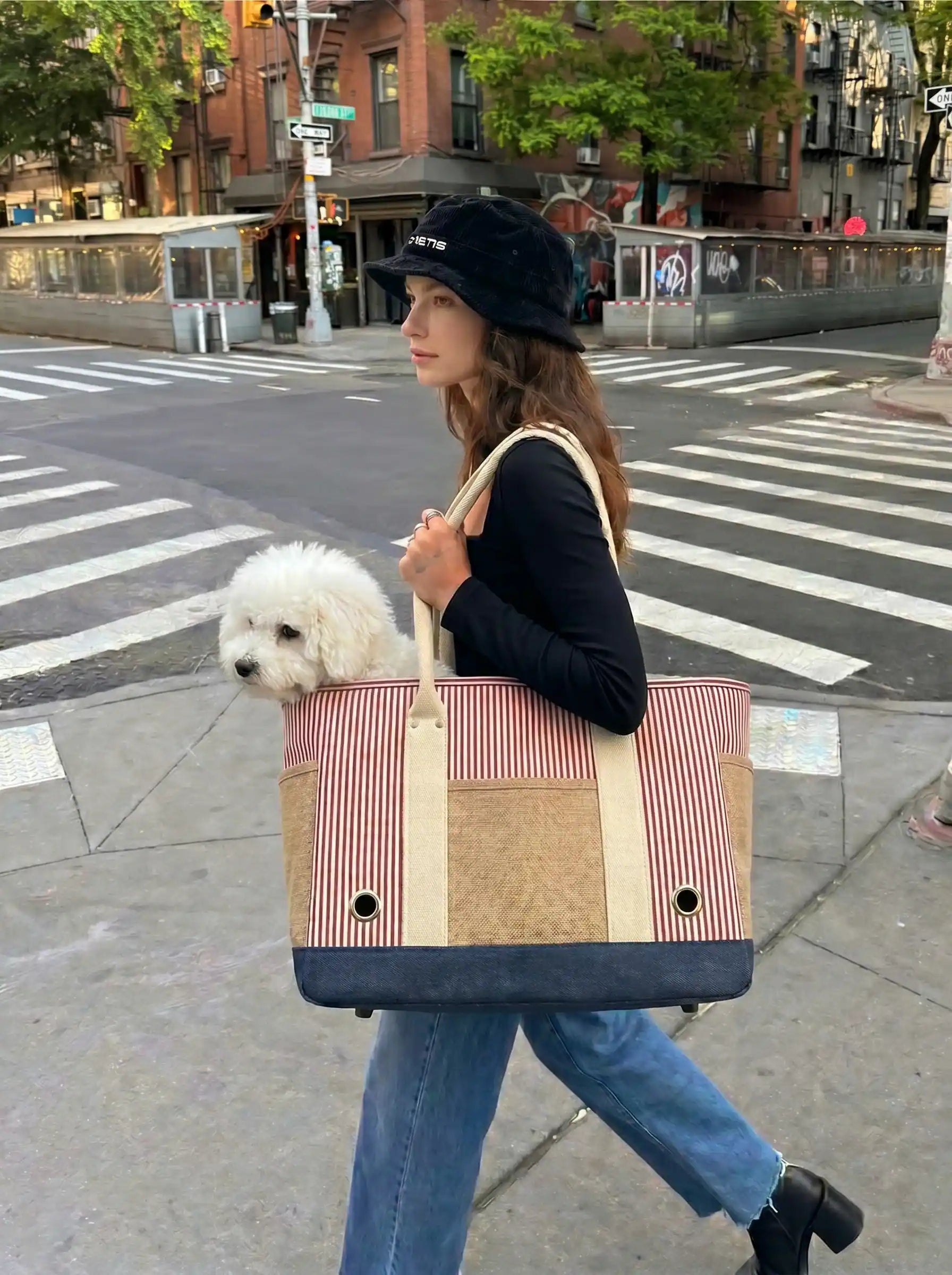 The model was walking on the street with a striped tote bag containing a beagle on her back.
